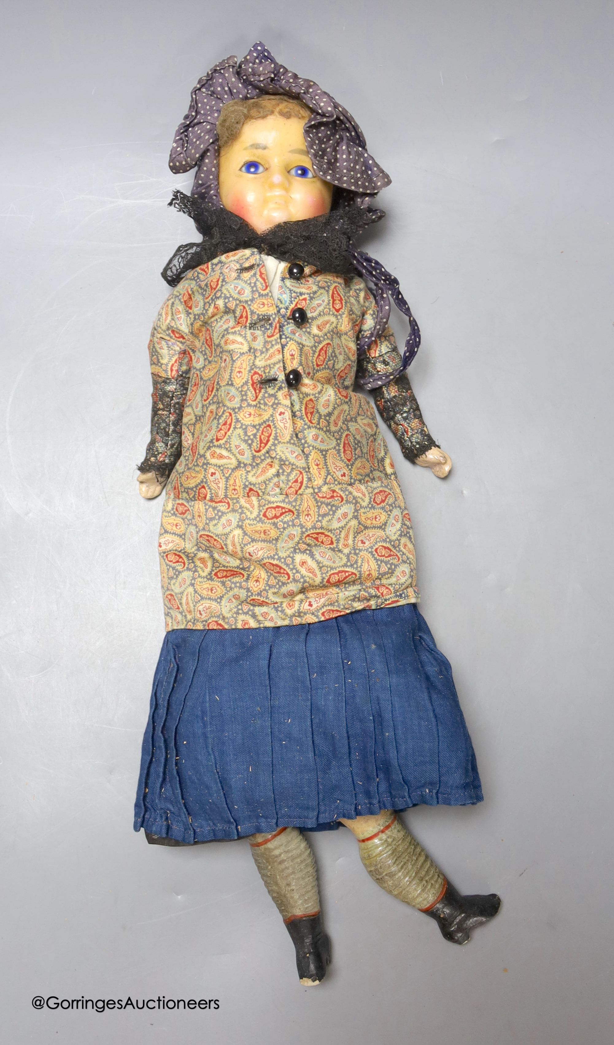 A wax composition doll, In early clothing, one leg detached but present, 18ins